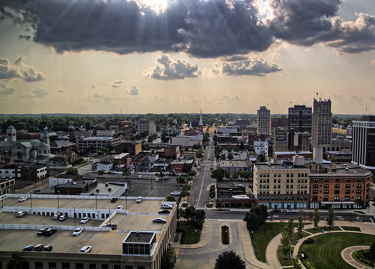 Aerial view of a cityscape with sunbeams shining through the clouds over buildings and streets.