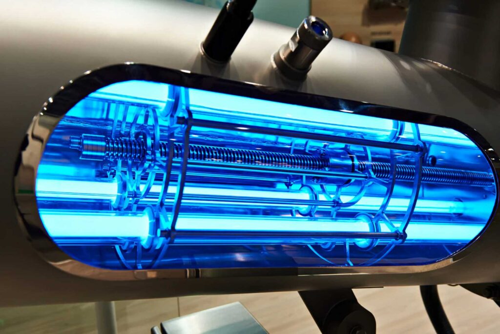 Close-up of an industrial water softening machine part with visible internal components illuminated by blue light, showcasing intricate mechanical details.