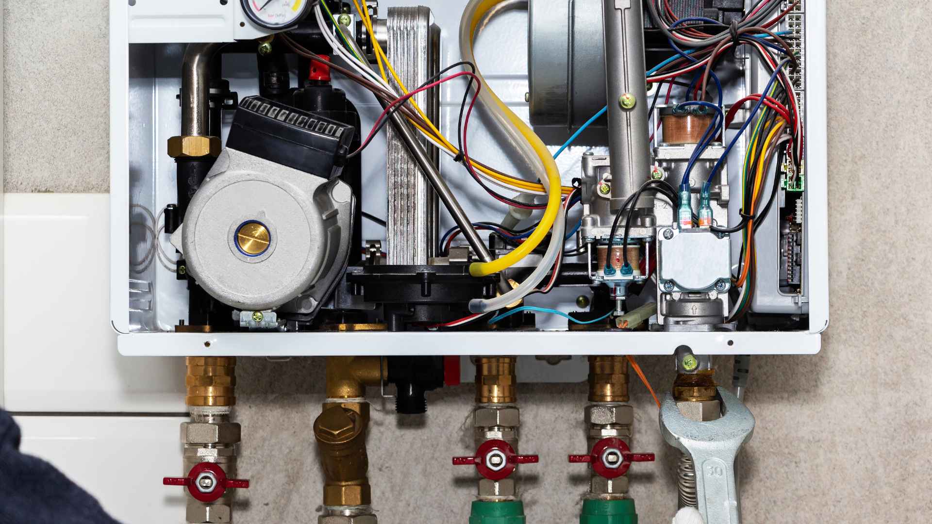 Interior of a modern boiler with visible intricate wiring and components, including pipes, valves, and gas lines.