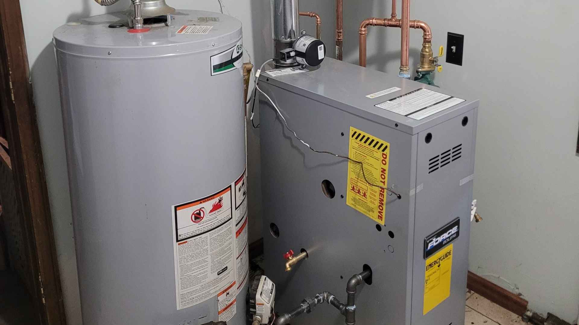 A residential basement with a water heater and a furnace connected to a gas line, both featuring various pipes and labels.