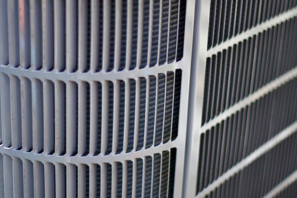 Close-up of a gray metal air conditioner grille with a pattern of vertical and diagonal lines following a tub replacement.