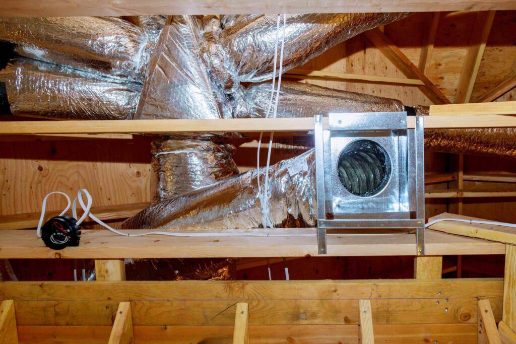 An HVAC system with ductwork installed in an attic, featuring insulated flex ducts and a metal ventilation unit.