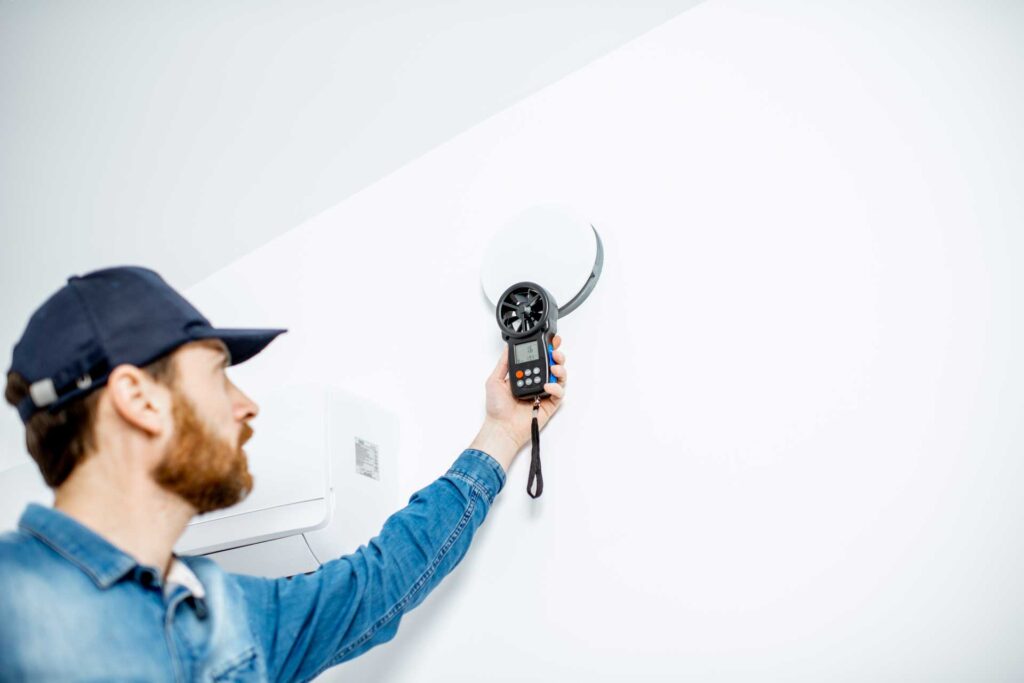 A technician using a digital device to measure or test a tub replacement electrical fixture on a white wall.
