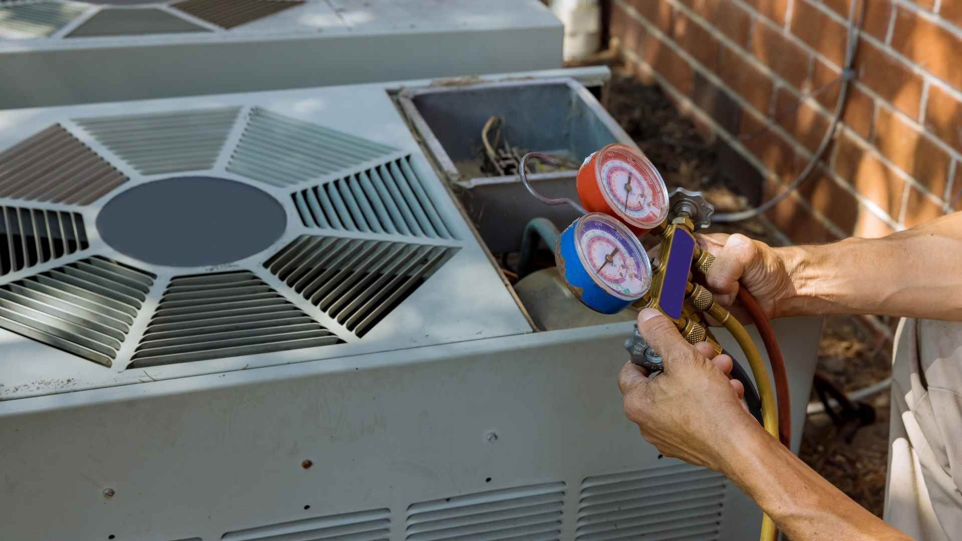 A person inspects HVAC units with a gauge tool