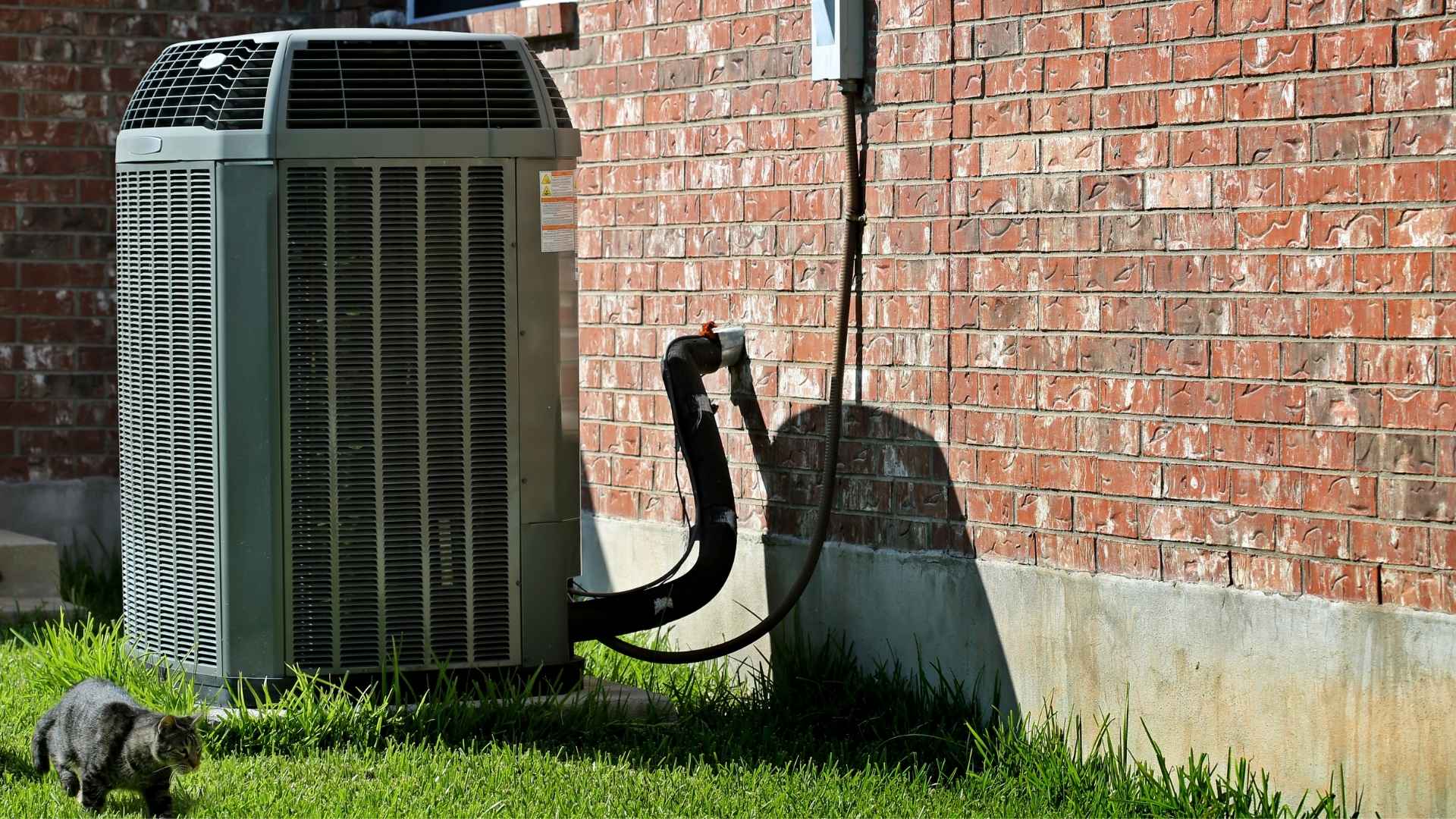 An air conditioning unit is next to a brick wall.