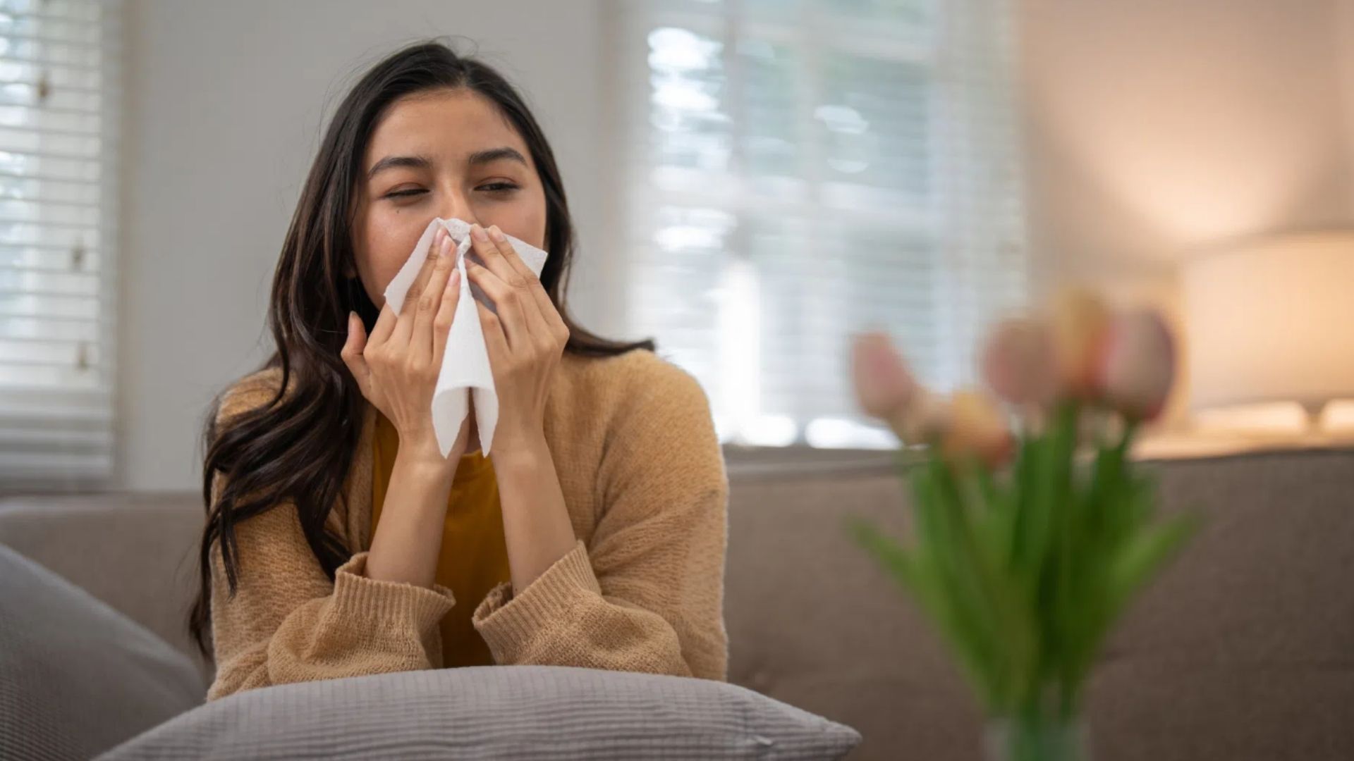 Woman Sneezing and blowing nose on a couch