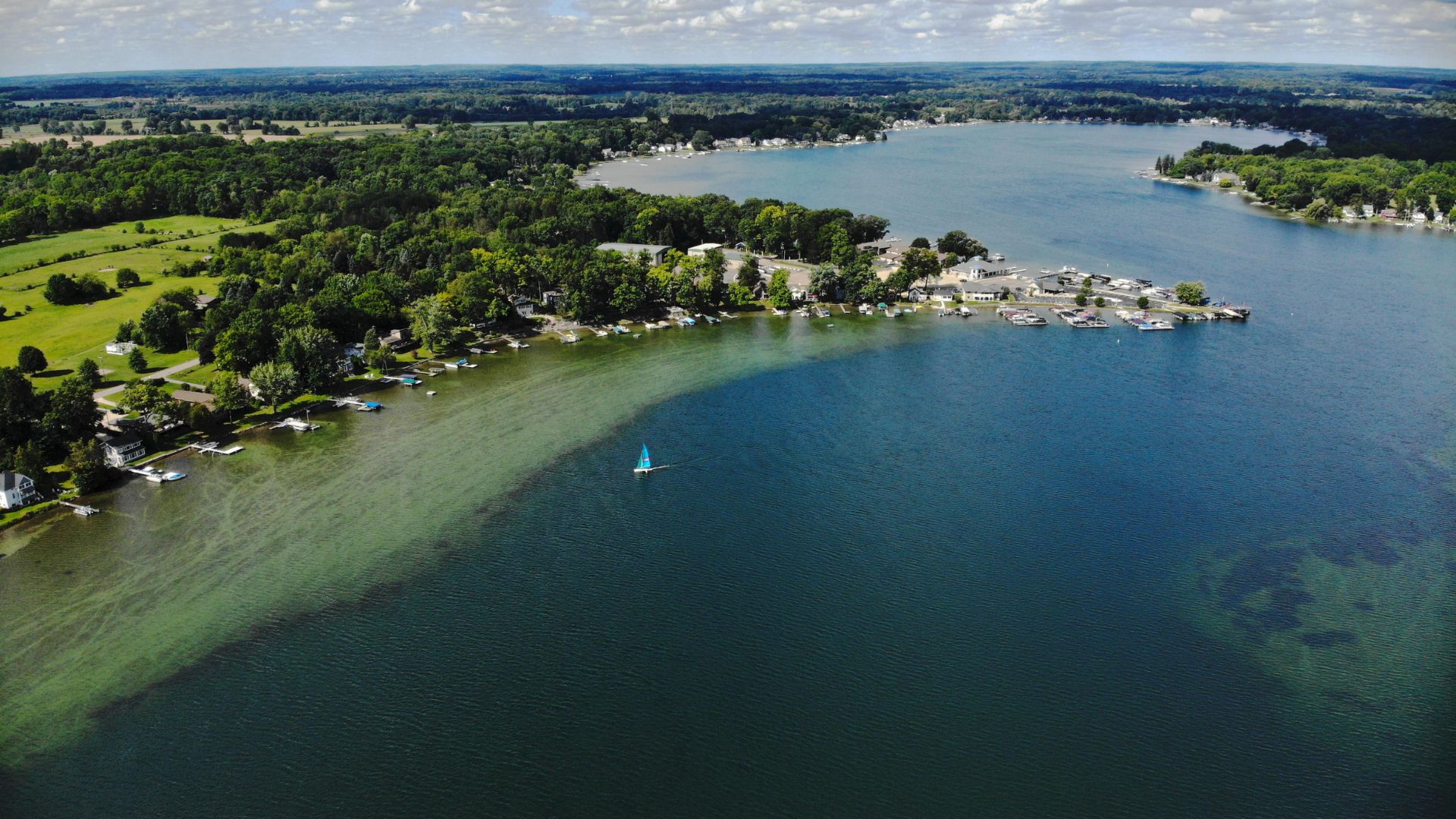 Aerial view of a lake with a single sailboat