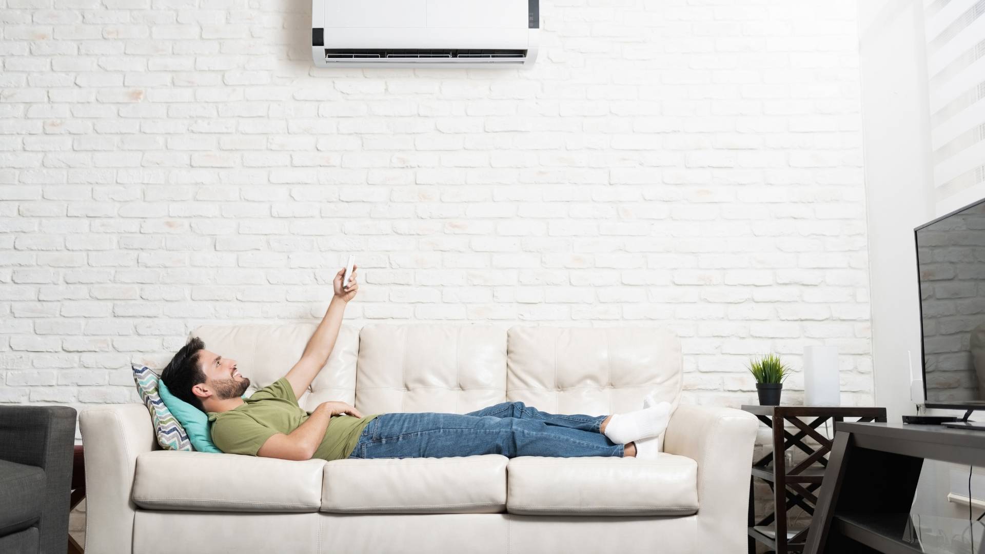 Person laying on white couch in living room enjoying a ductless mini-split from home