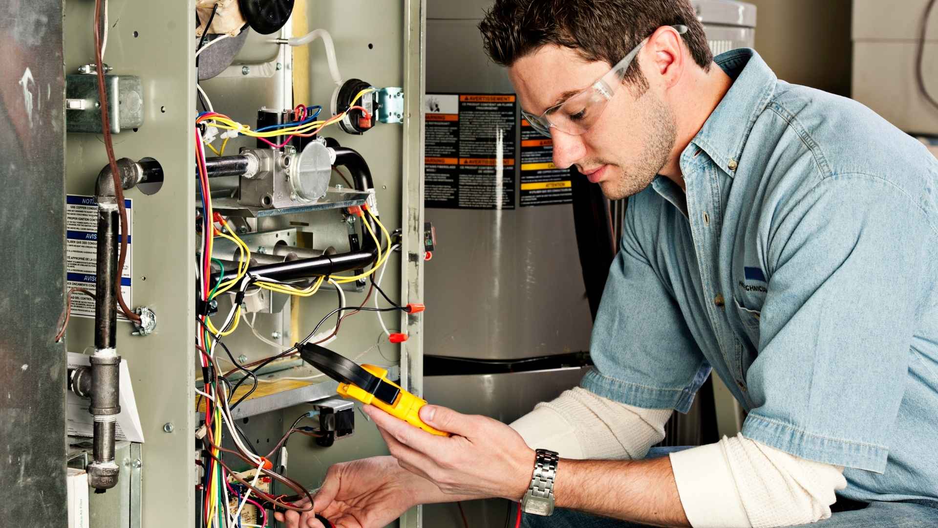 A technician wearing safety glasses uses a multimeter